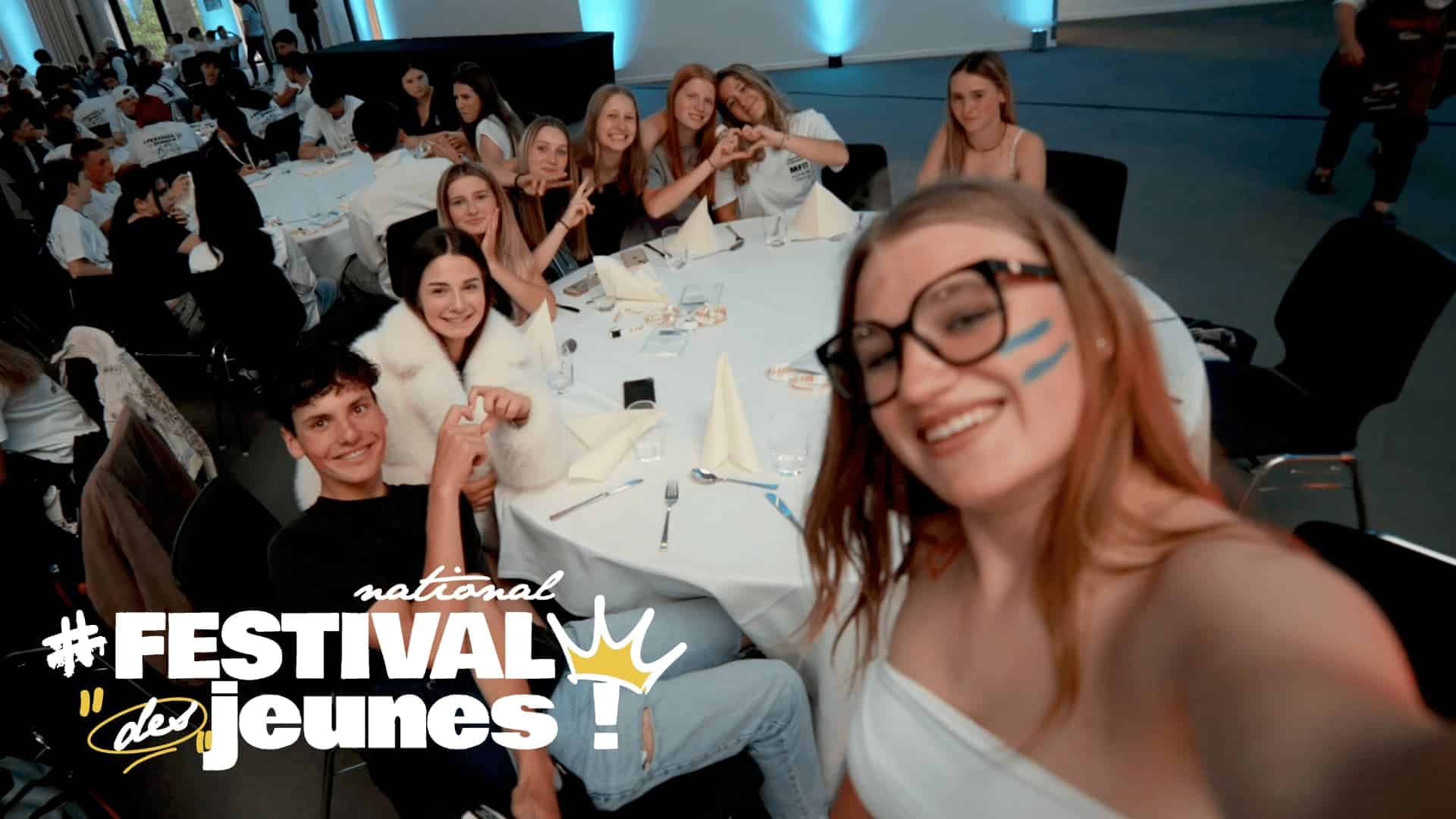 Jeunes rassemblés autour d’une table lors du dîner du Festival national des jeunes MFR, souriants et faisant des cœurs avec les mains pendant une selfie festive